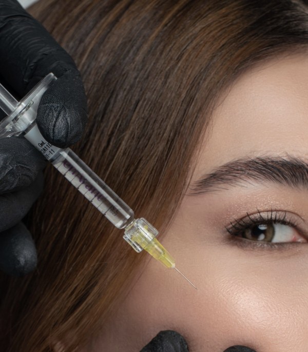 Syringe with a fine needle just under the eye, black-gloved hands