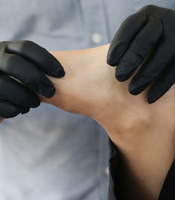 Black-gloved hands holding a bare foot