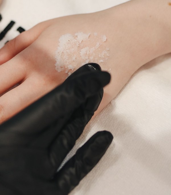 Black-gloved hand smoothing cream onto the back of a hand